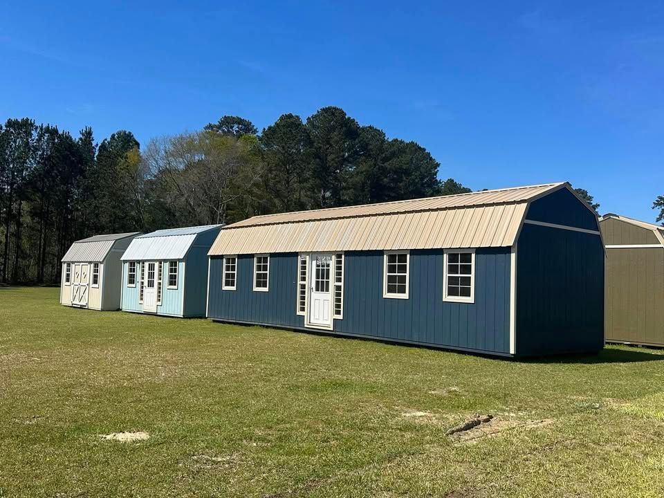 Row of colorful storage sheds in a grassy field, under a bright blue sky.