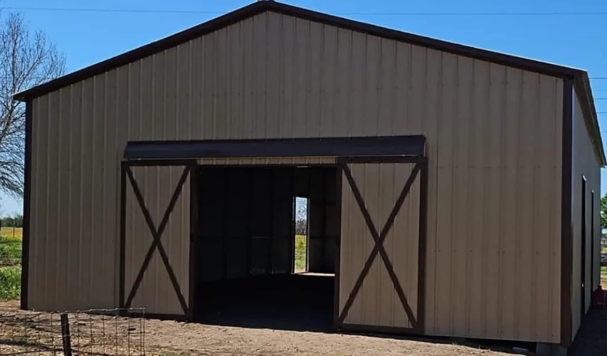 Tan and brown metal barn with open sliding doors.