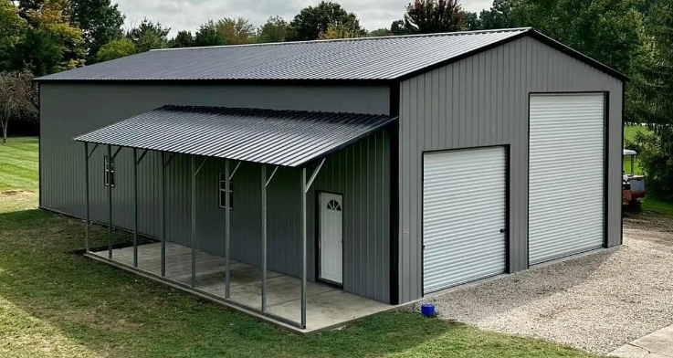 Gray metal building with a porch, two garage doors, and a door on a grassy lot.