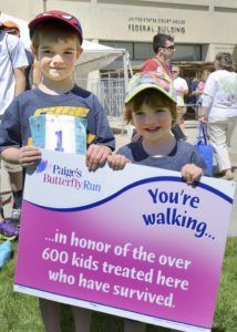 Two children holding a sign that says you 're walking in honor of the over 600 kids treated here who have survived