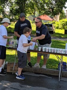 A group of people are standing around a table selling drinks.