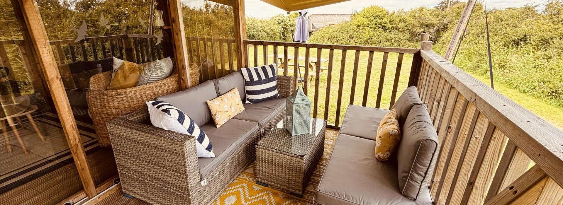 Outdoor seating area with gray wicker furniture, patterned pillows, and a glass-topped coffee table.