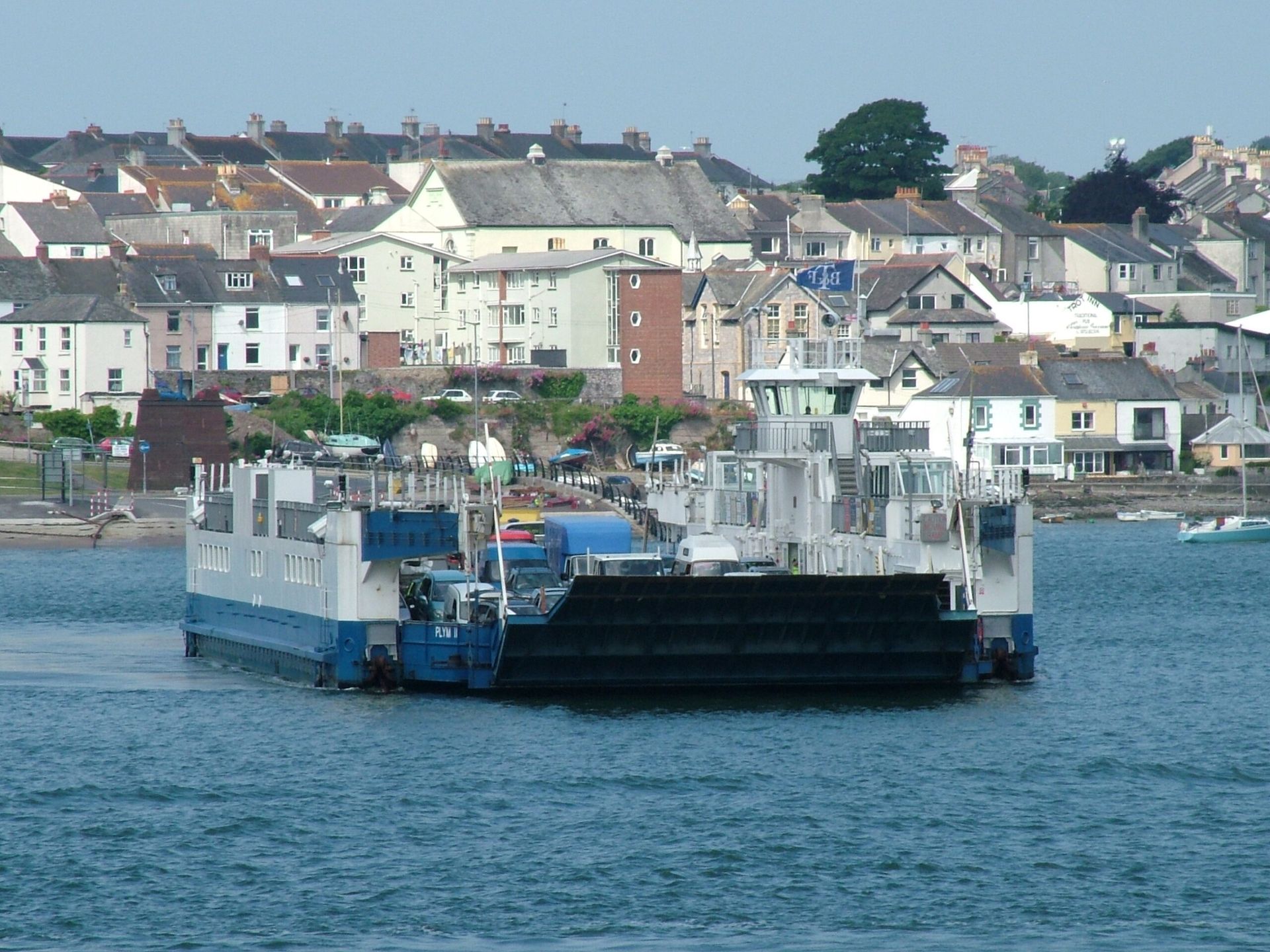 Blue and white ferry in water with a town in the background.