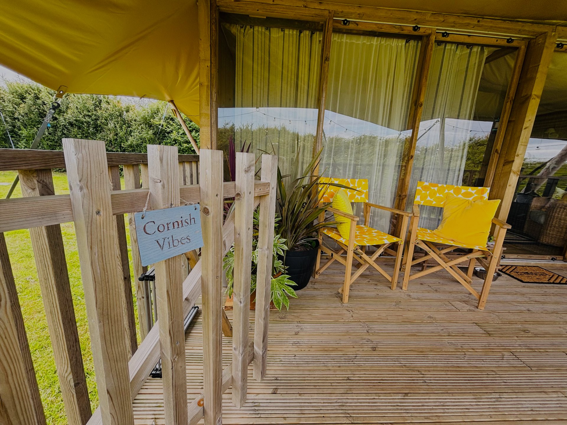 Wooden porch with two yellow chairs and a sign that says 