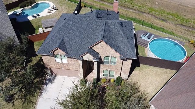 Roofer on a sloped roof replacing a slate tile, working near a vent.