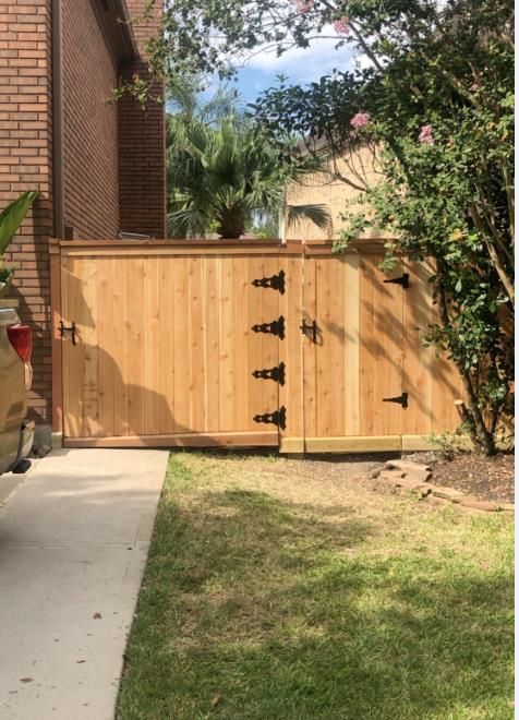 Stack of vertical slat replacement fence panels in a residential backyard, prepared for installation.