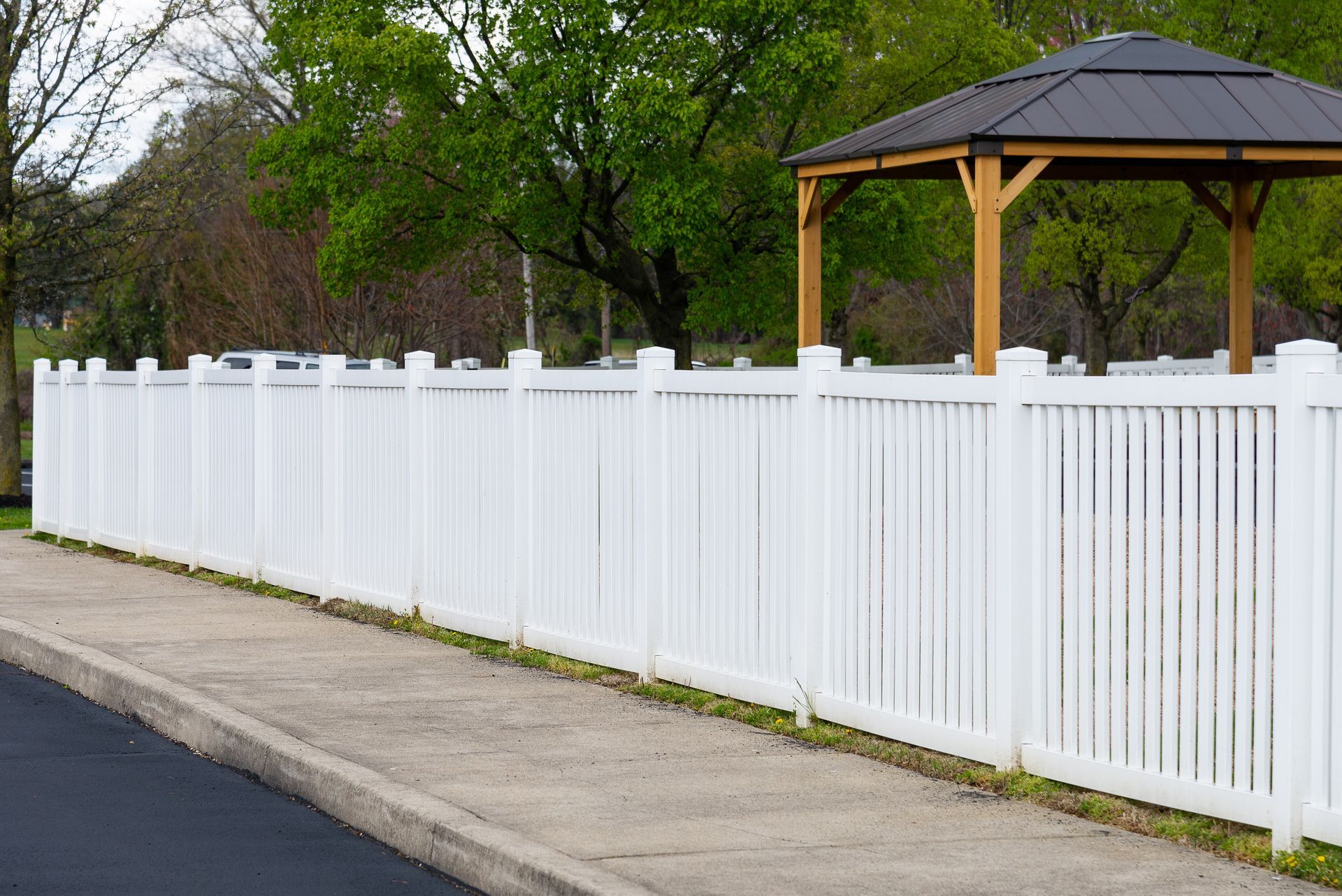 Scenic view of a well-maintained white vinyl fence surrounding a private backyard.