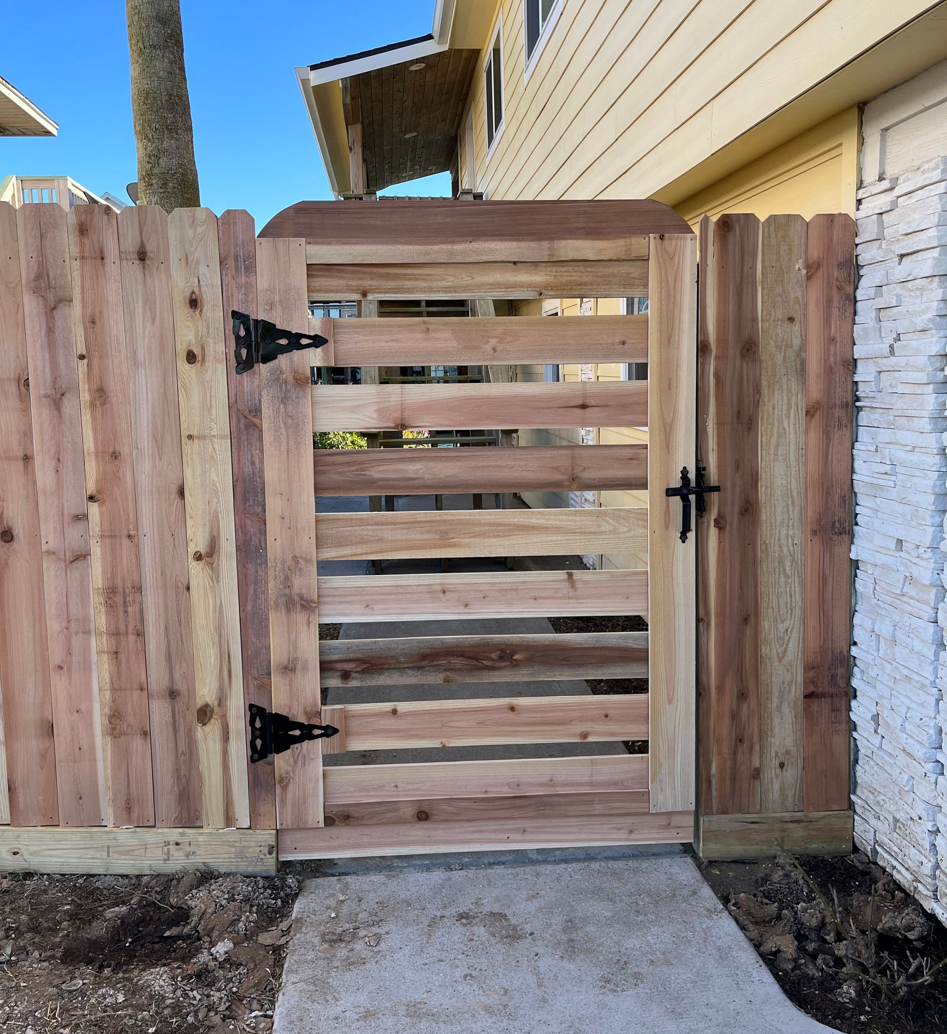 Stack of vertical slat replacement fence panels in a residential backyard, prepared for installation.