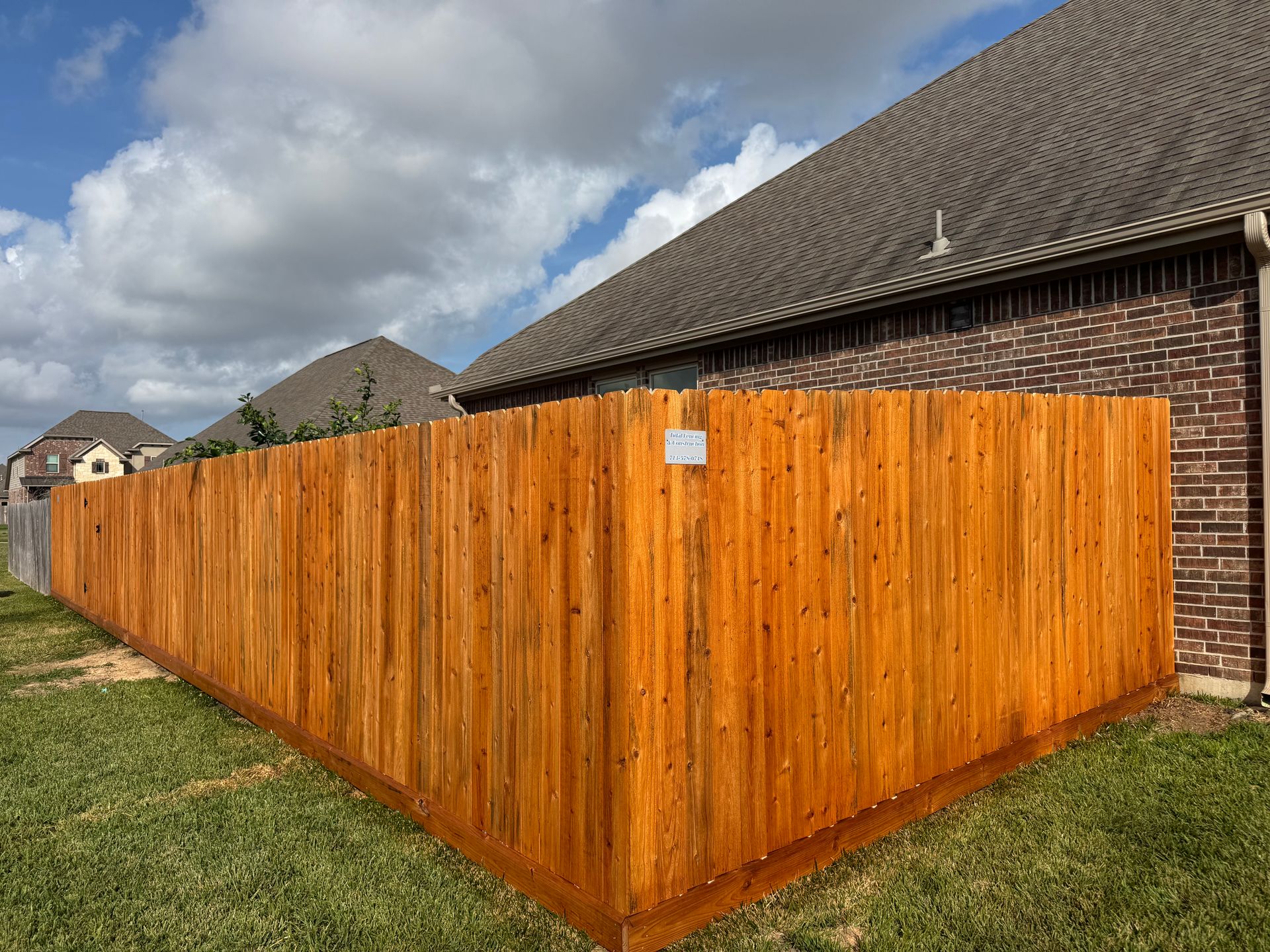Stack of vertical slat replacement fence panels in a residential backyard, prepared for installation.