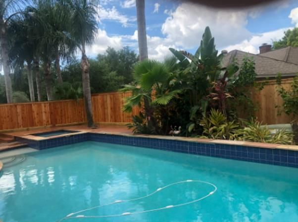 Stack of vertical slat replacement fence panels in a residential backyard, prepared for installation.