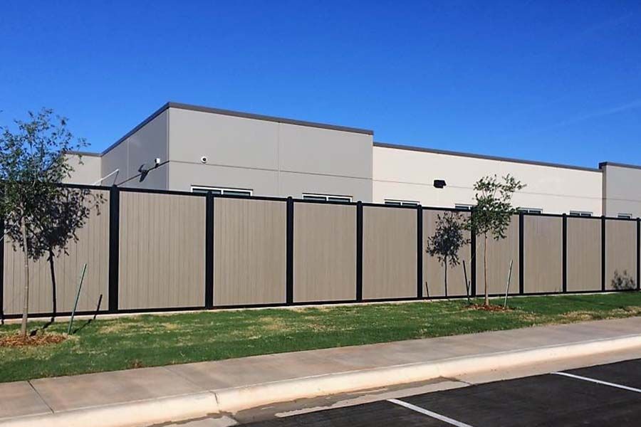 Scenic view of a well-maintained white vinyl fence surrounding a private backyard.