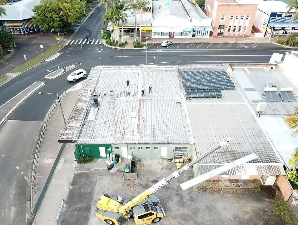 An Aerial View of a Crane Working on the Roof of a Building — Monty's Metal Roofing In Ocean Shores, NSW