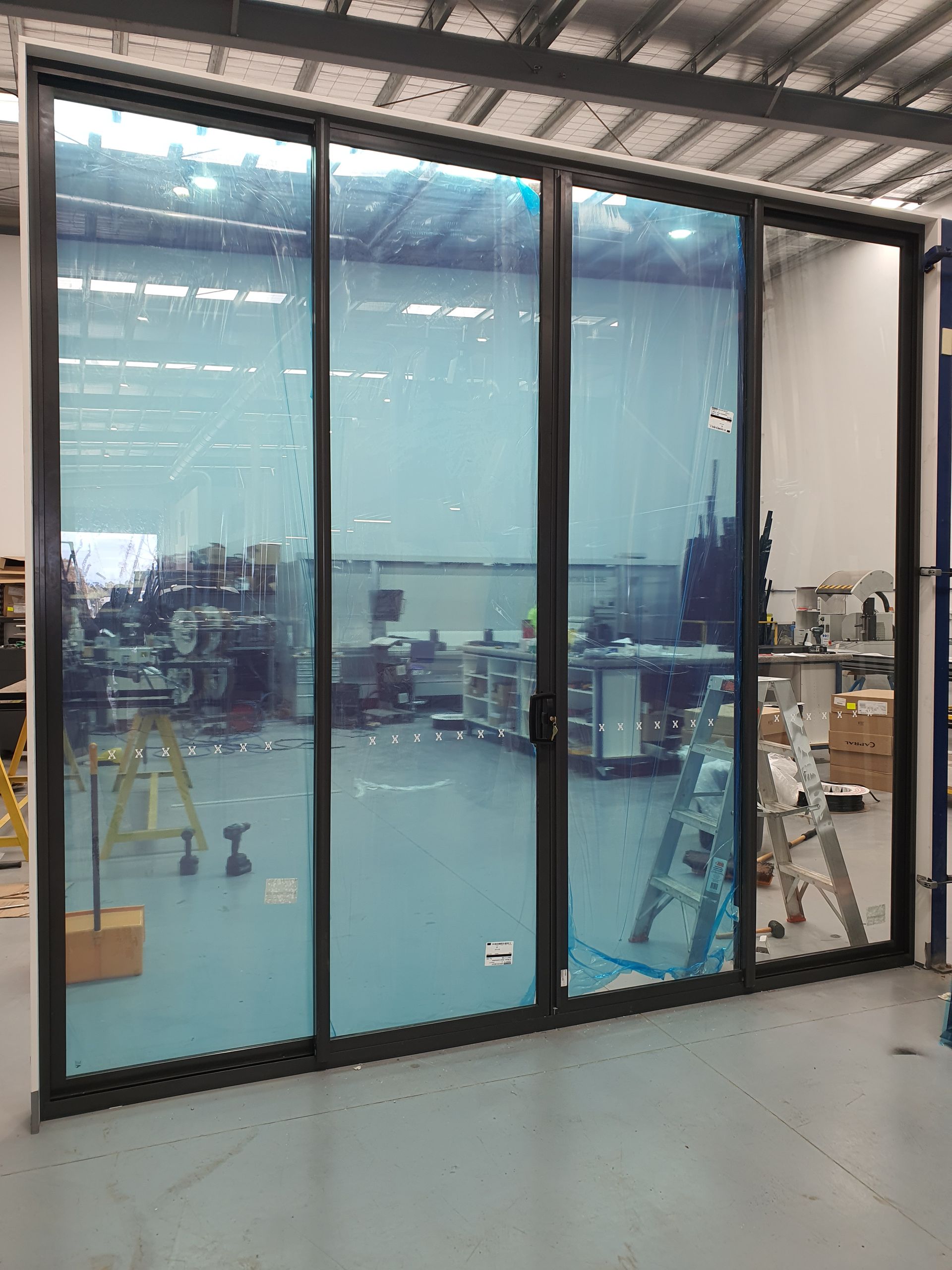 Large glass wall under construction with blue protective film in an industrial interior