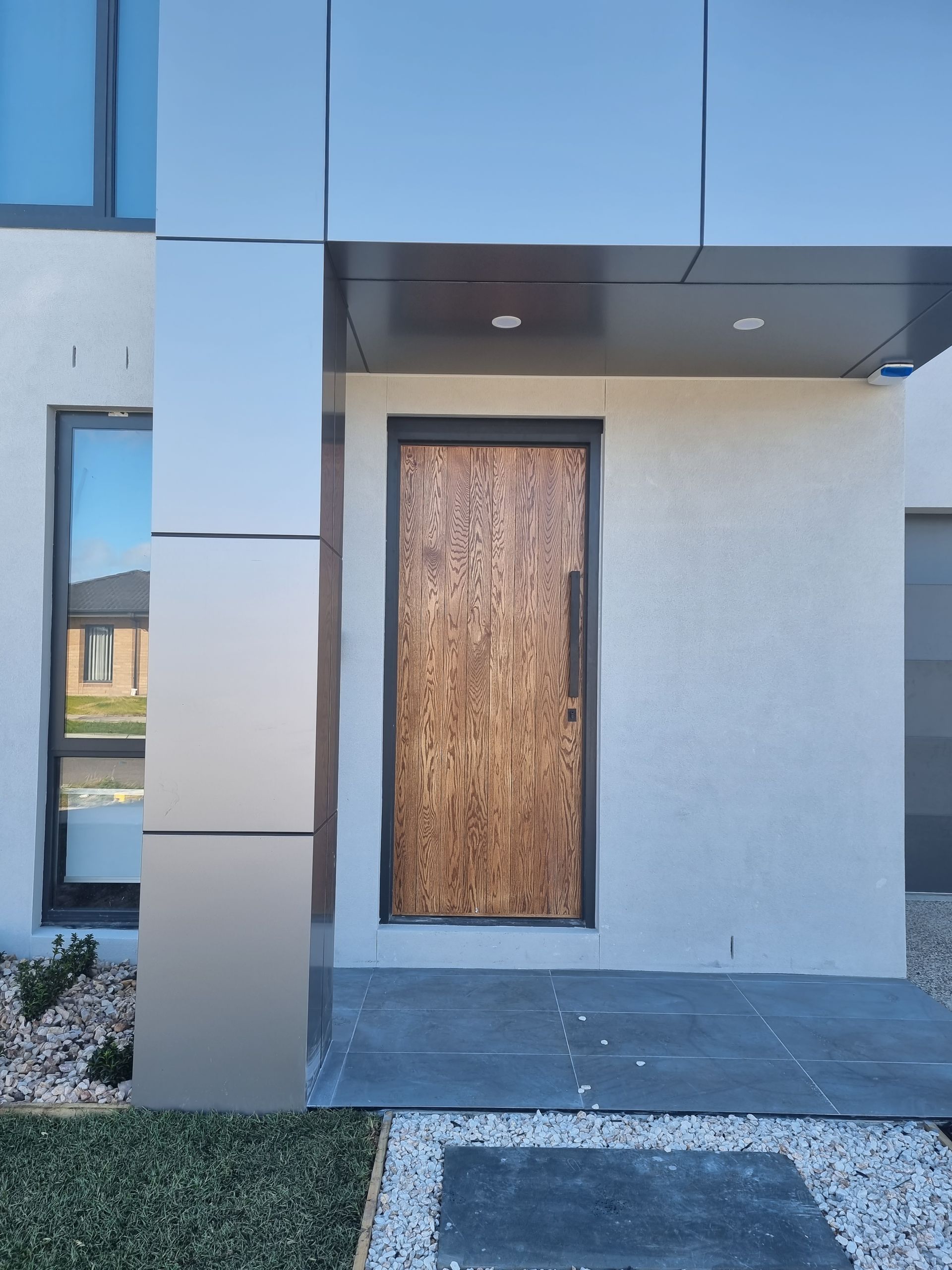 Modern house entrance with a boarded-up front door and gray exterior siding