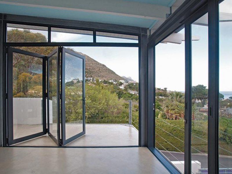 Open glass doors leading to a balcony with mountain and greenery views.