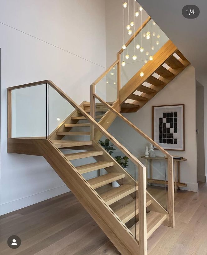 Modern wooden staircase with glass railing in a bright, minimalist interior room