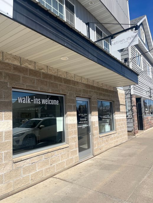 Brown mug and two haircare products next to a plant on a shelf.