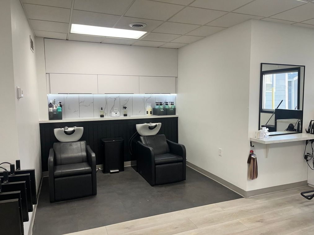 Hair salon interior with wash stations, chairs, and styling products.