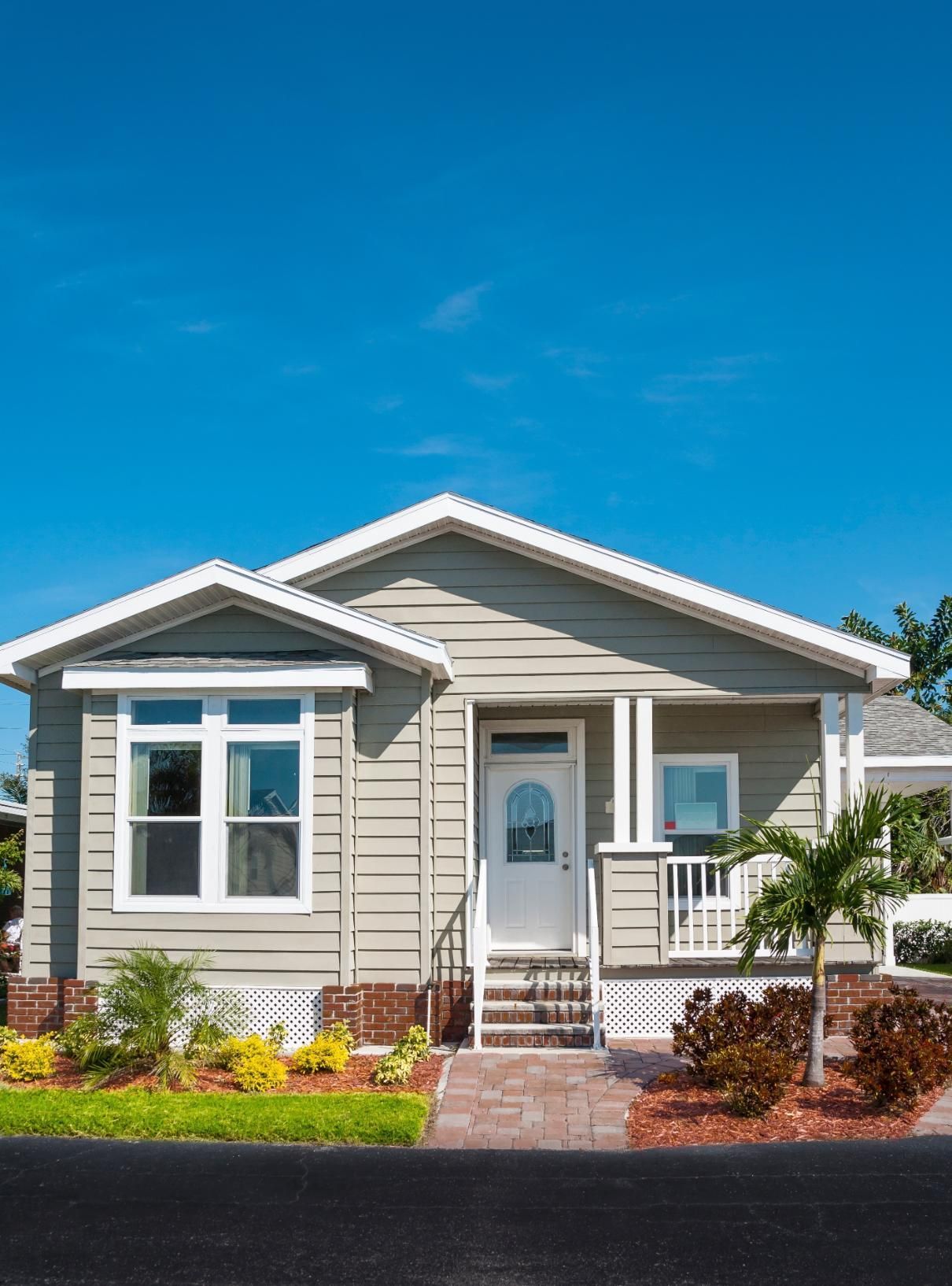Light green house with white trim, porch, and bay window; clear blue sky.