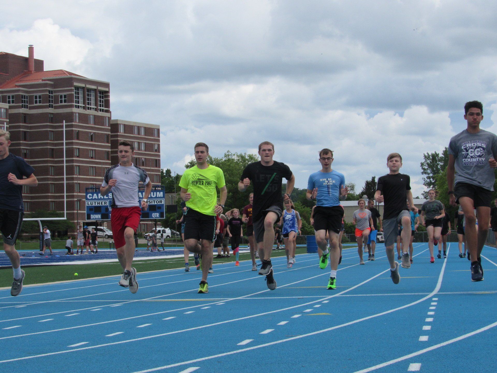 Male athletes running on track course toward the camera, low angle view.