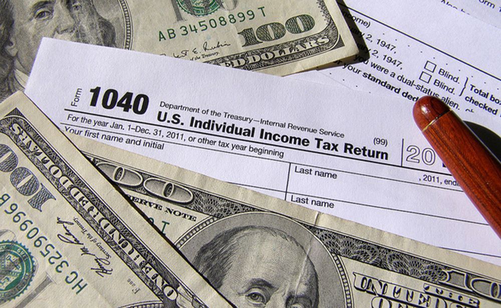 1040 u.s. individual income tax return form on top of a pile of money