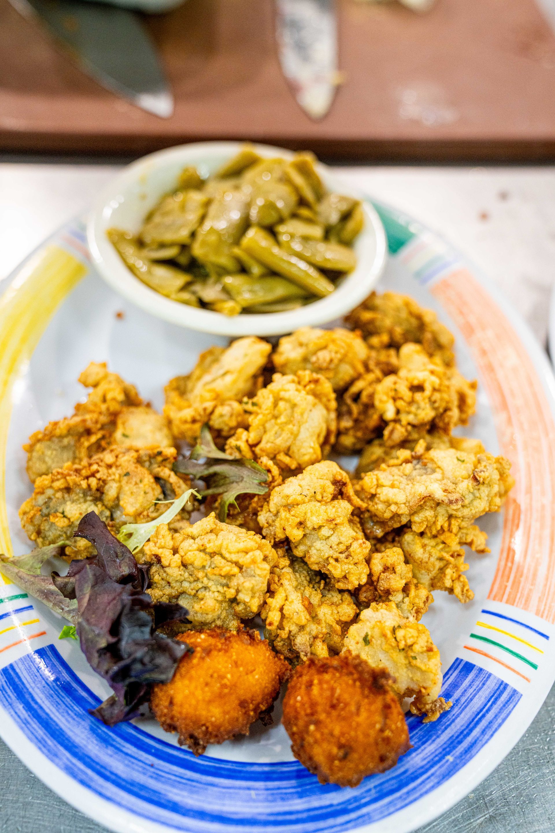 A plate of food with fried oysters and green beans on a table.