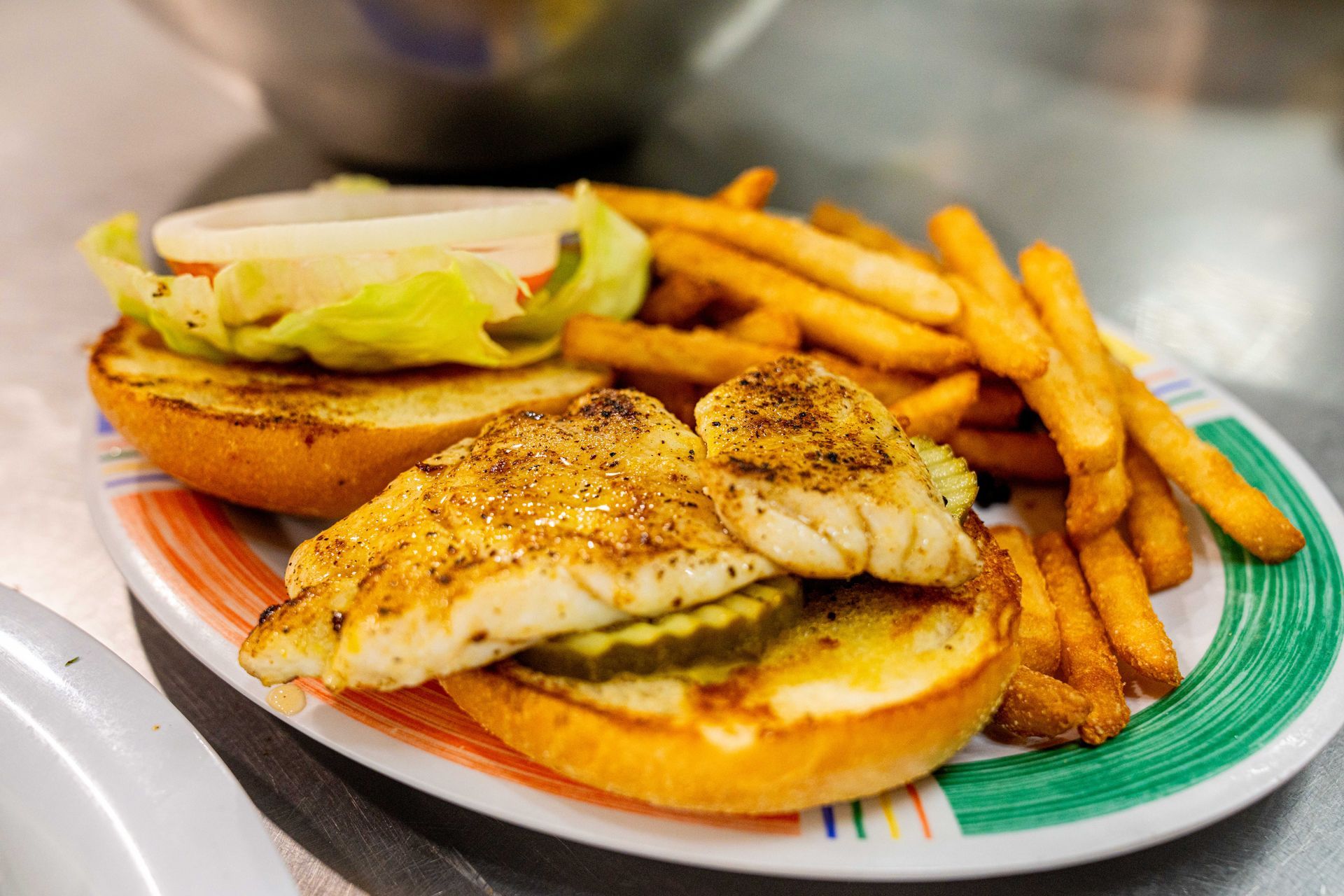 A fish sandwich with french fries on a plate.