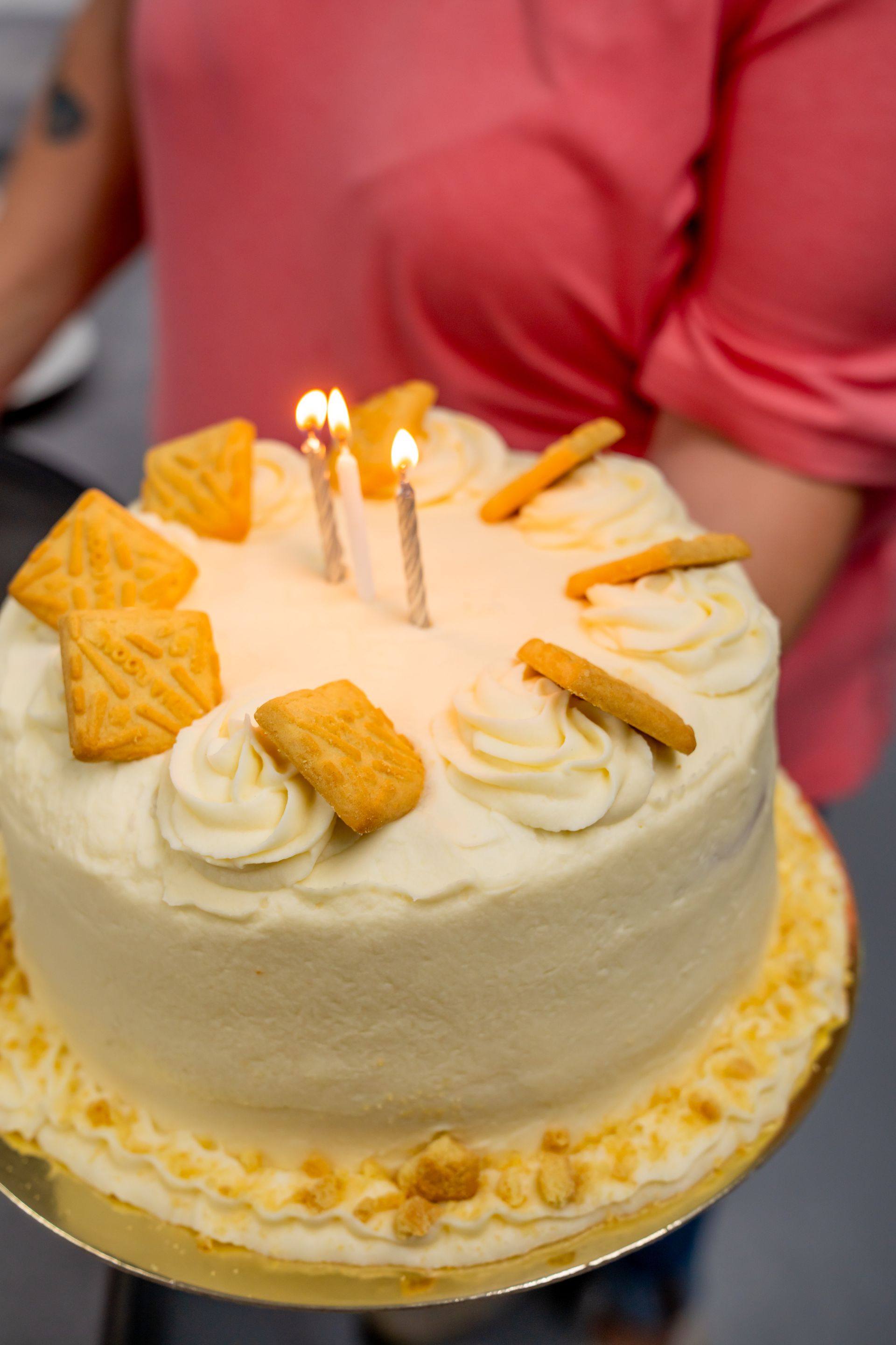 A woman is holding a birthday cake with candles on it.