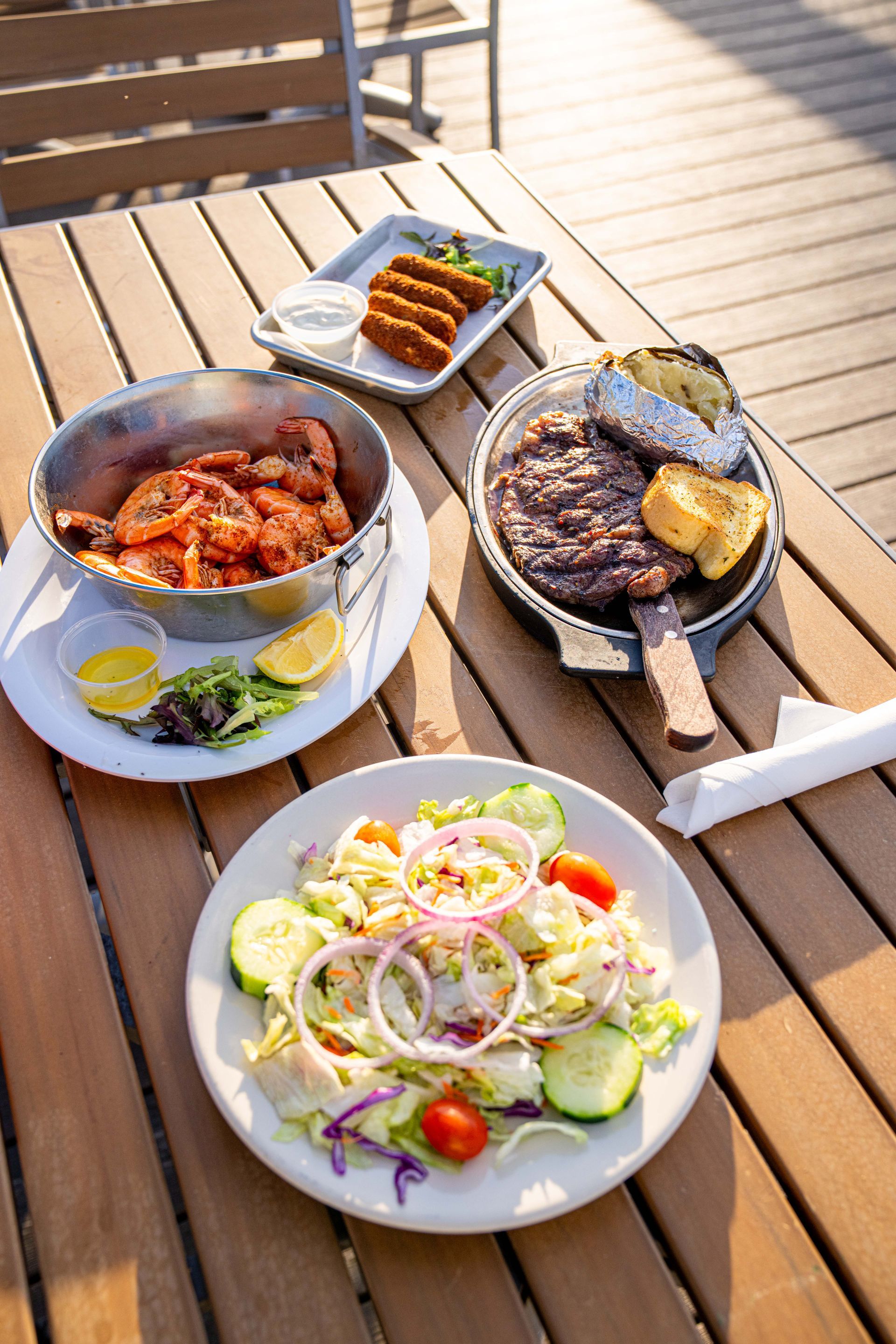 Three plates of food are sitting on a wooden table.