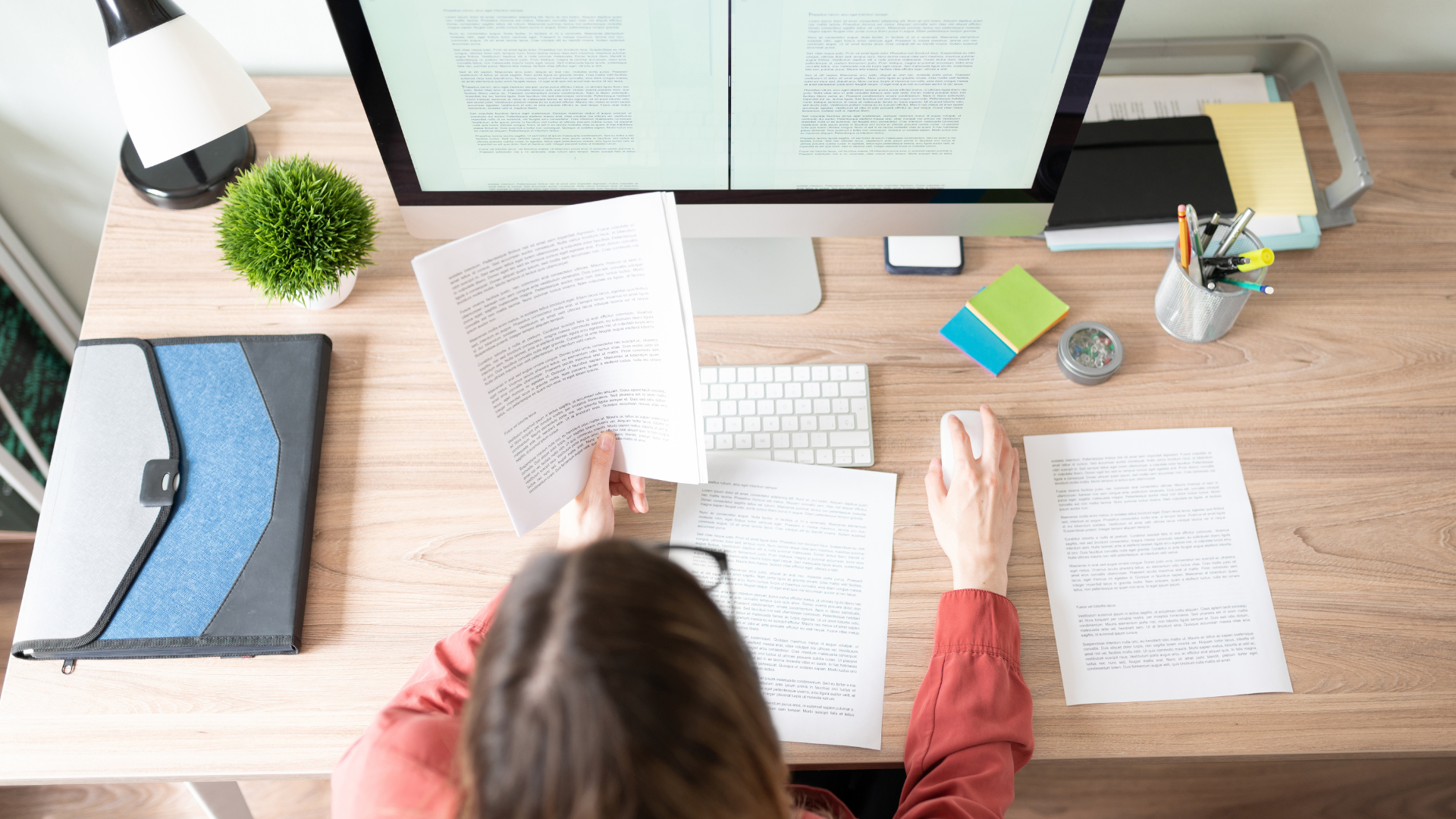 A woman is sitting at a desk with a computer and papers.