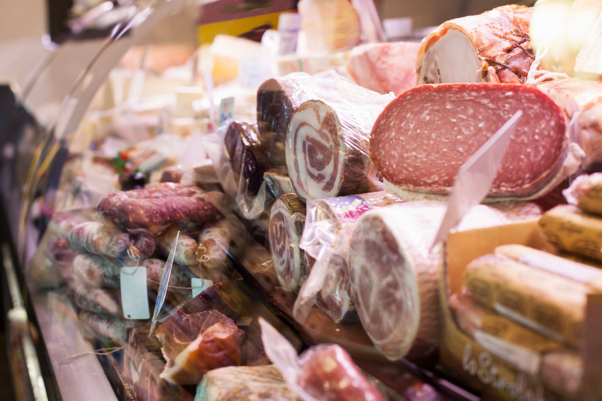 Vetrina piena di salumi vari: salame, salsiccia e altro ancora.