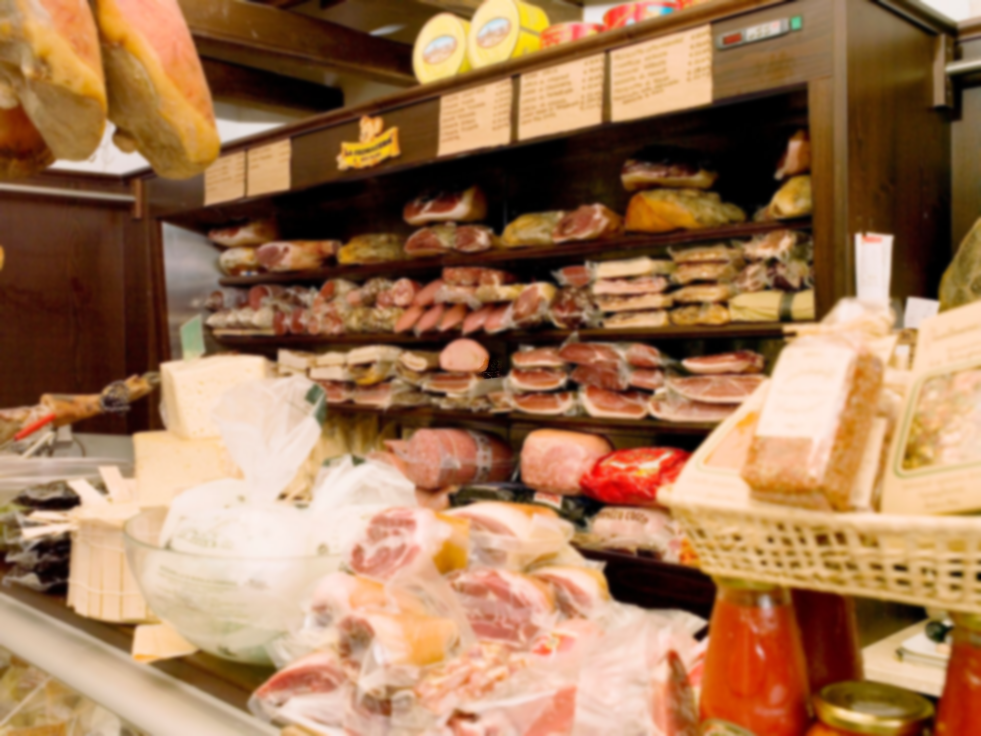 Un banco gastronomia che espone vari salumi, formaggi e prodotti alimentari preparati.