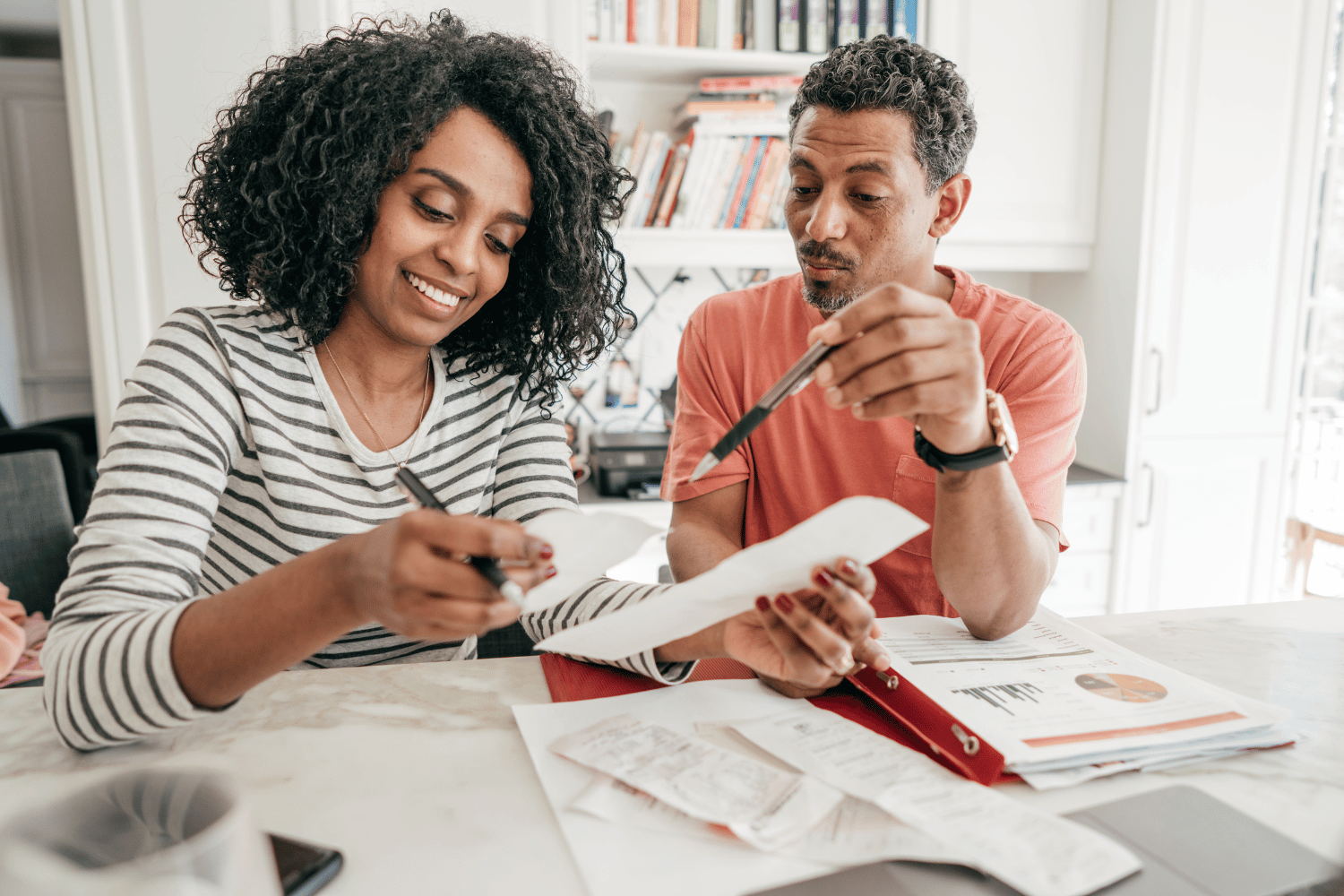 A man and a woman are sitting at a table looking at papers.