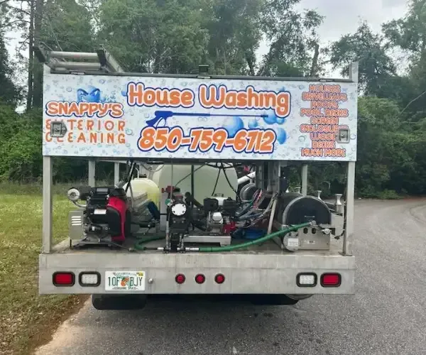 A truck with a house washing setup, logo includes phone number and exterior cleaning services.