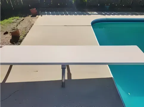 White diving board over a blue swimming pool.