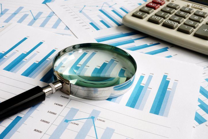 Business papers with financial report and magnifying glass. Audit concept