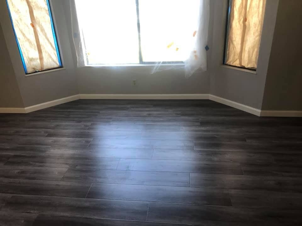 An empty room with a wooden floor and two windows.