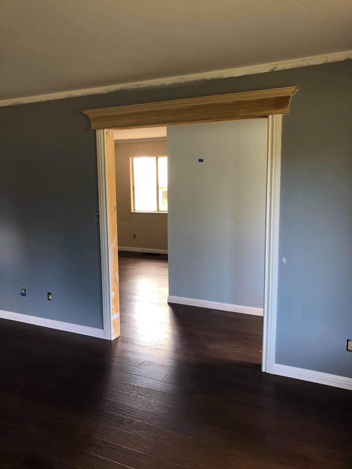 An empty room with a wooden floor and a doorway leading to another room.