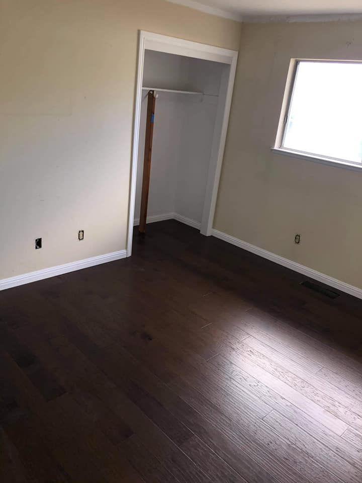 An empty room with hardwood floors and a window.