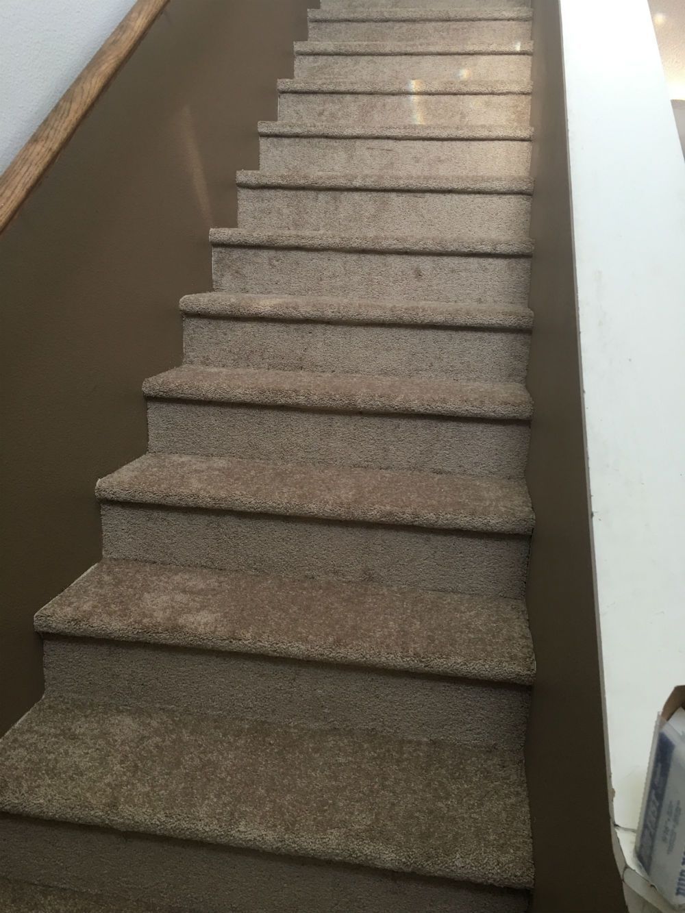 A set of stairs with carpeted steps and a wooden railing