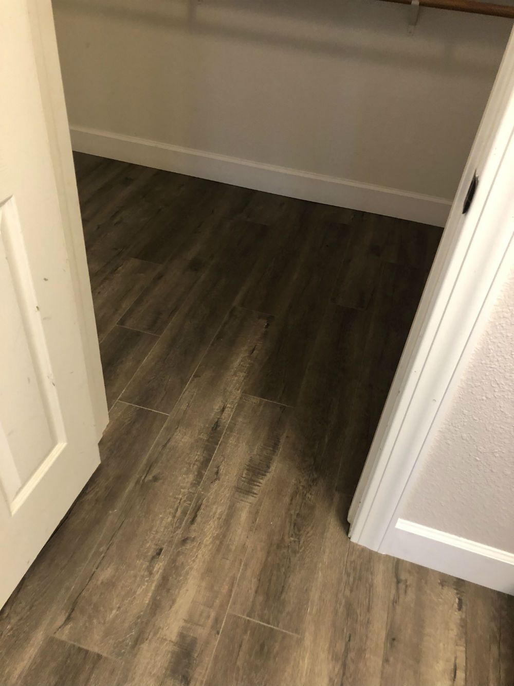 A closet with a wooden floor and a white door.