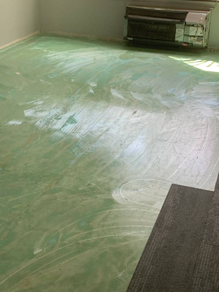 A room with a green floor and a piano in the background.