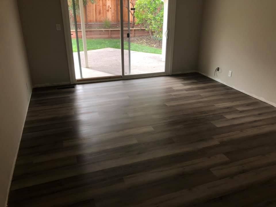 An empty living room with hardwood floors and a sliding glass door leading to a patio.