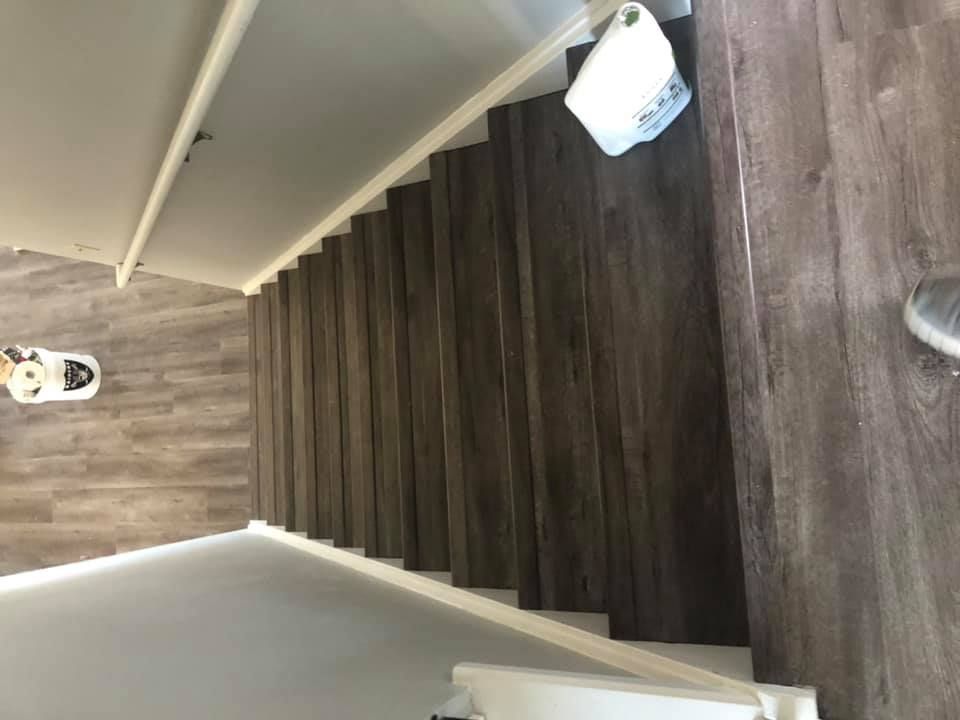 A person is standing on a set of wooden stairs in a house.