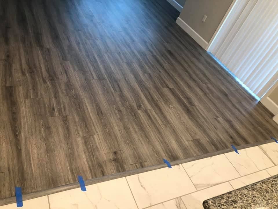A wooden floor in a living room with blue tape on it.