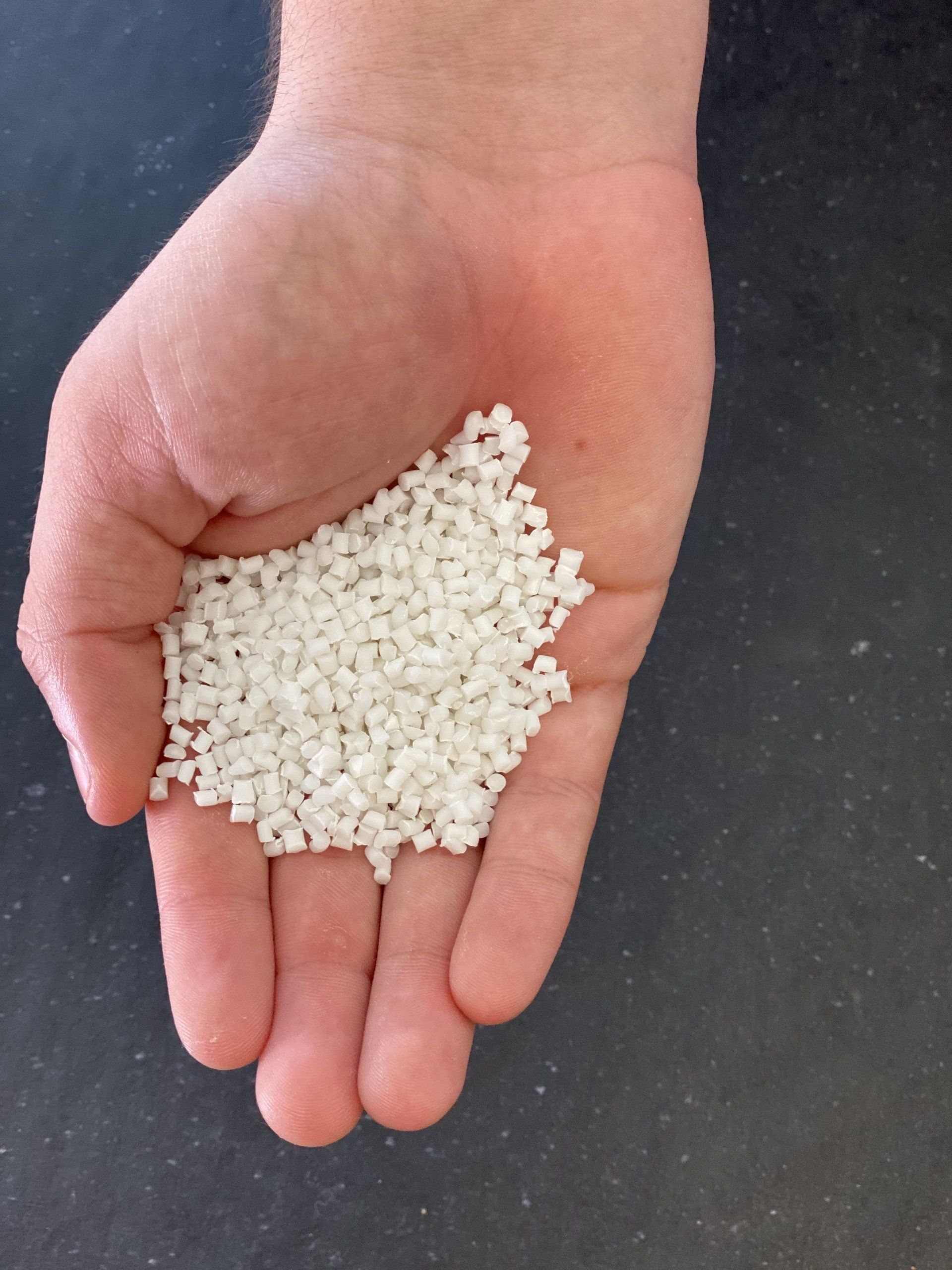 A hand is holding a pile of white granules