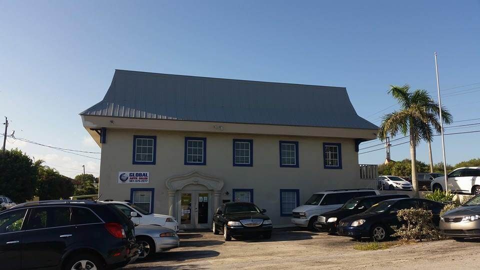 Two-story building with cars parked out front; blue accents around windows, gray roof; sunny day.