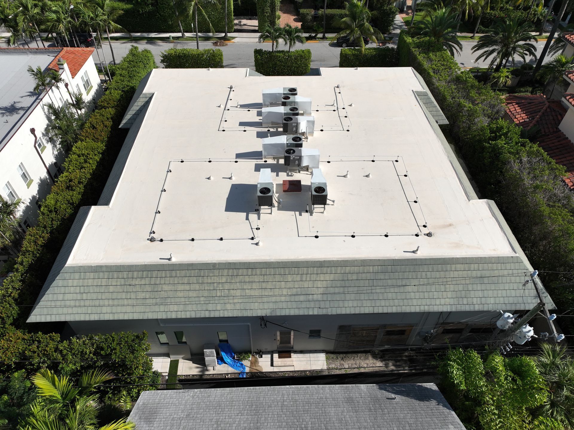 Aerial view of a flat roof with HVAC units, surrounded by green hedges.