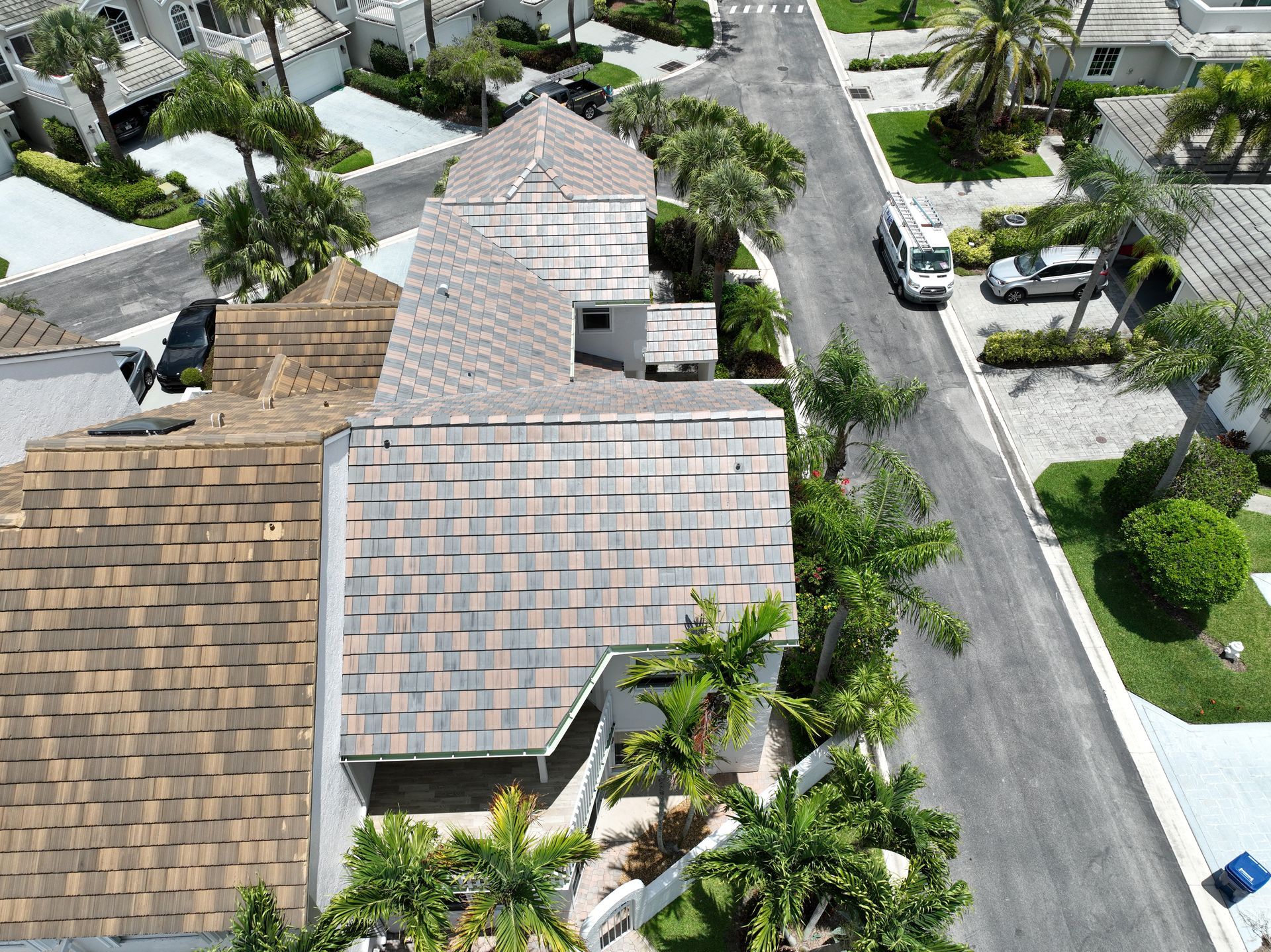 Aerial view of residential homes with brown roofs and a street.