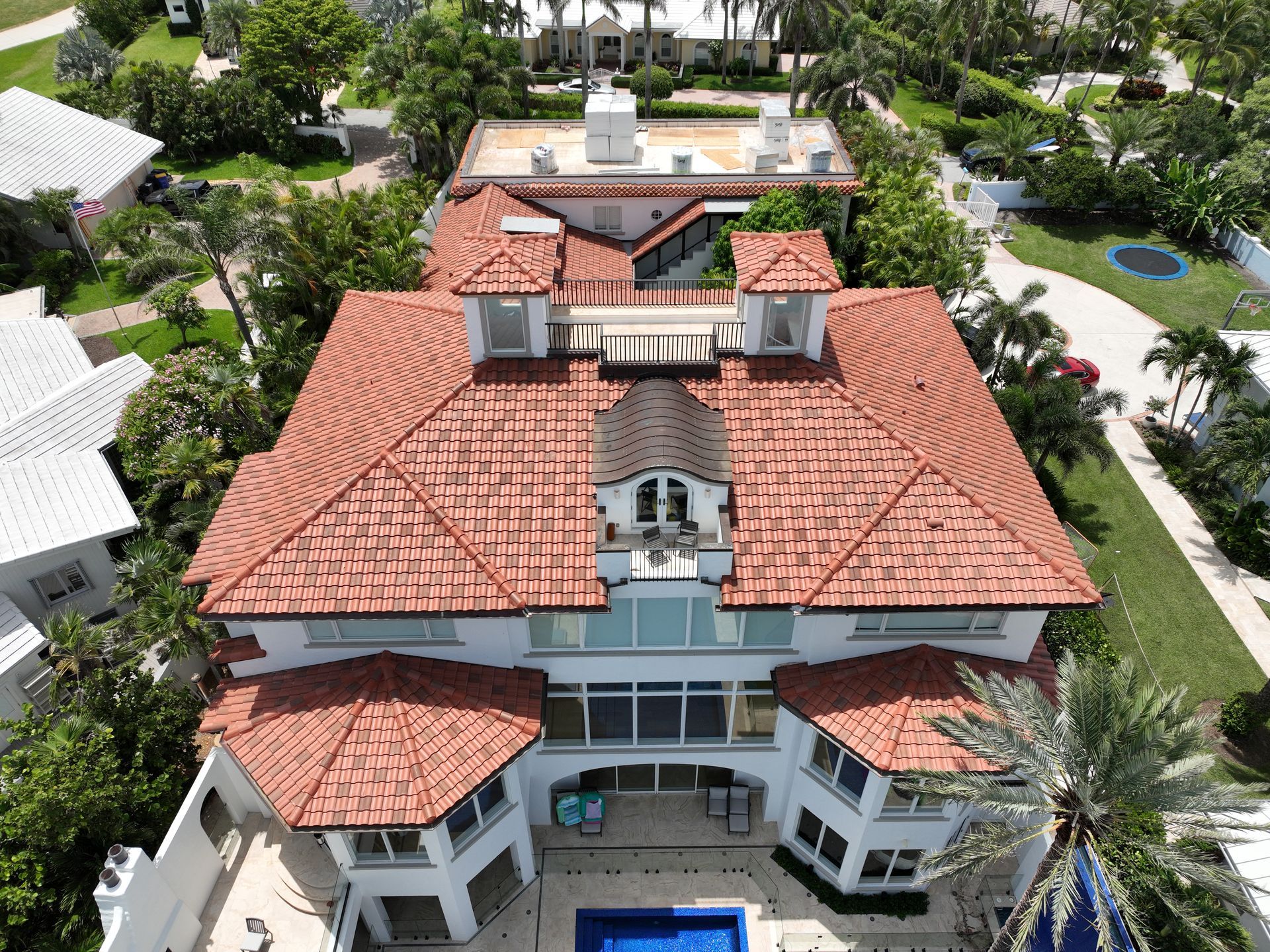 Aerial view of a large white house with a red tile roof and a pool.